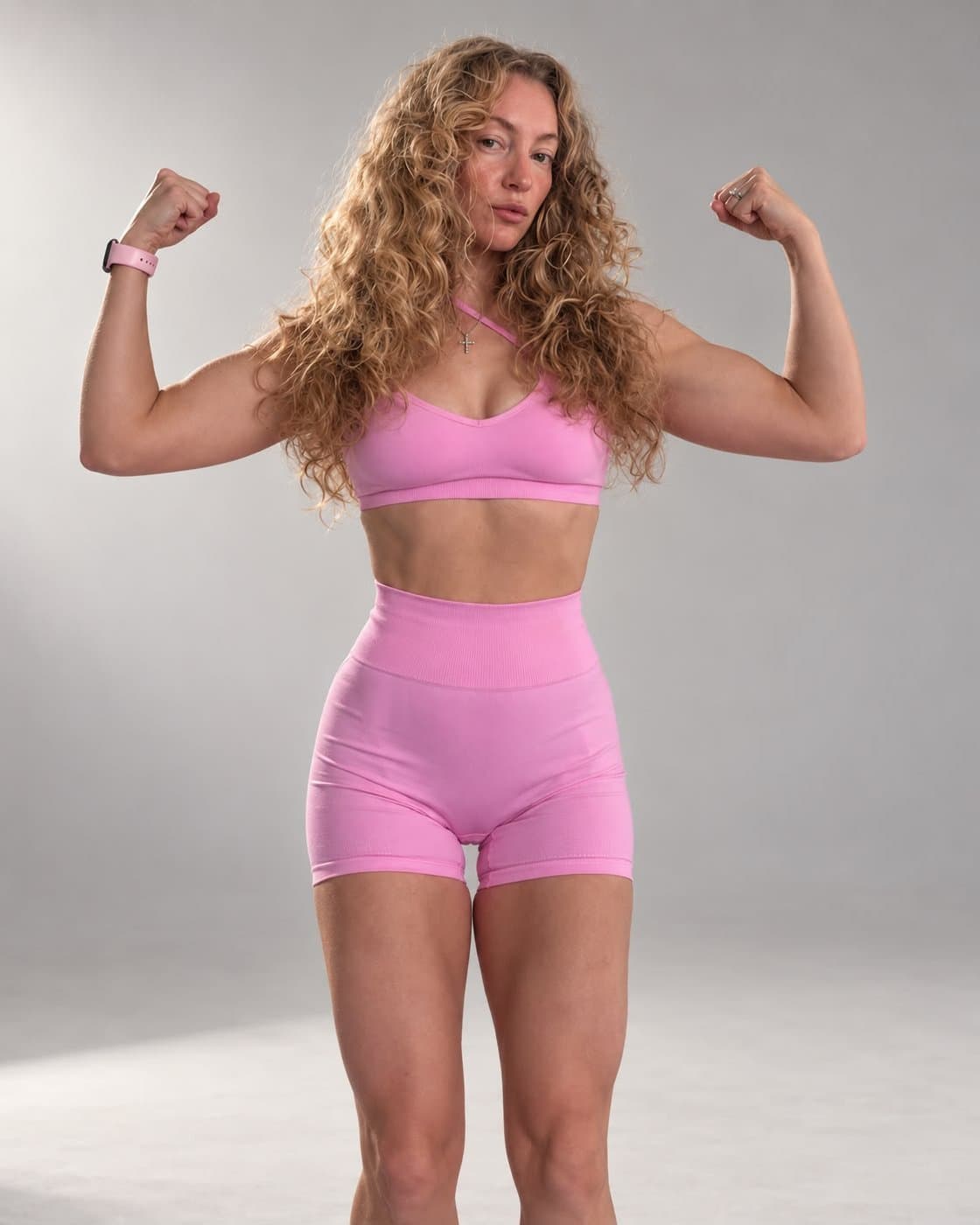 Kate in a pink set, flexing both arms